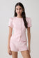 Woman wearing short sleeve pink satin top with matching shorts.