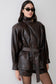 Woman wearing a dark brown faux leather cinch waist jacket.
