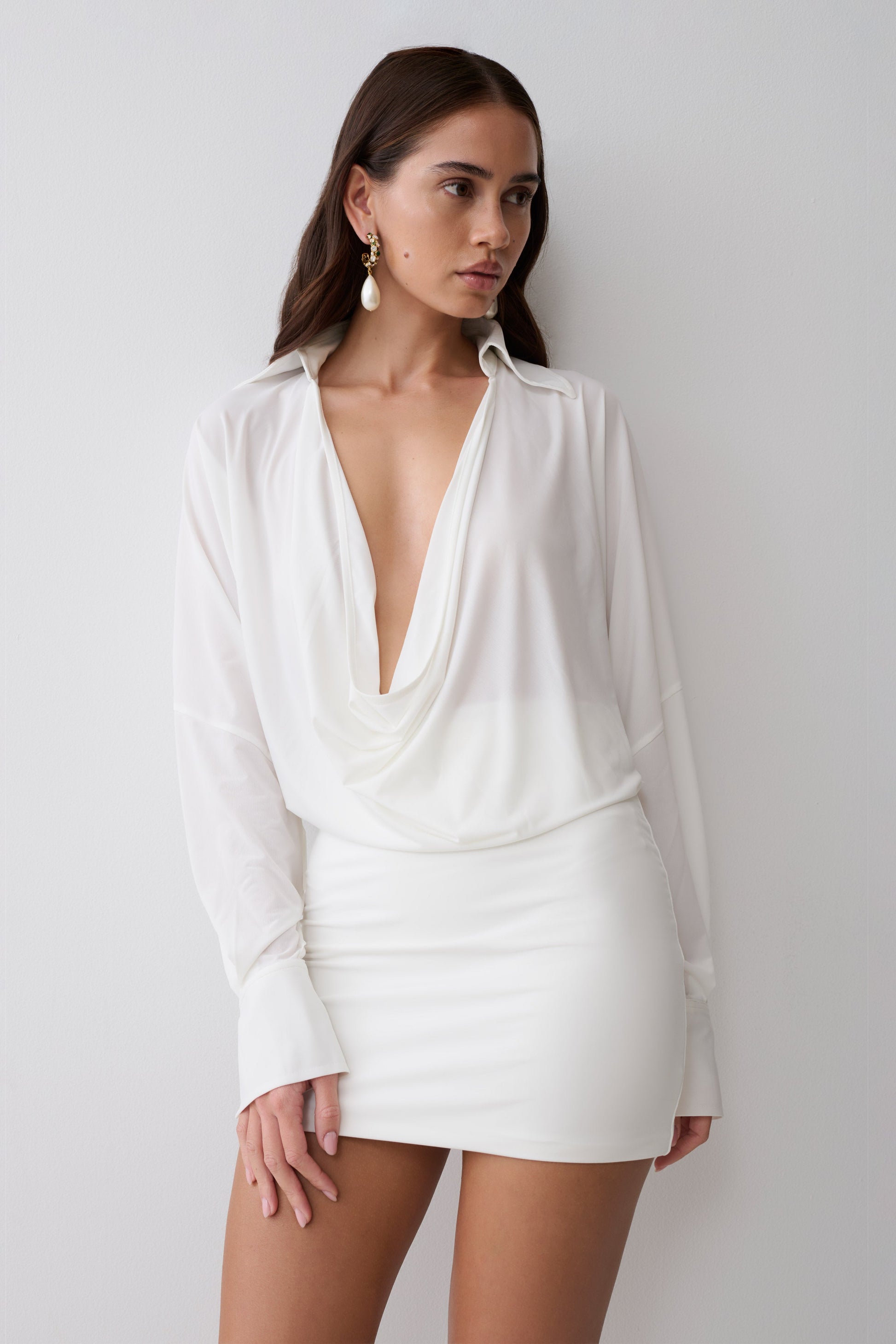 Woman wearing a white cowl drape shirt dress.