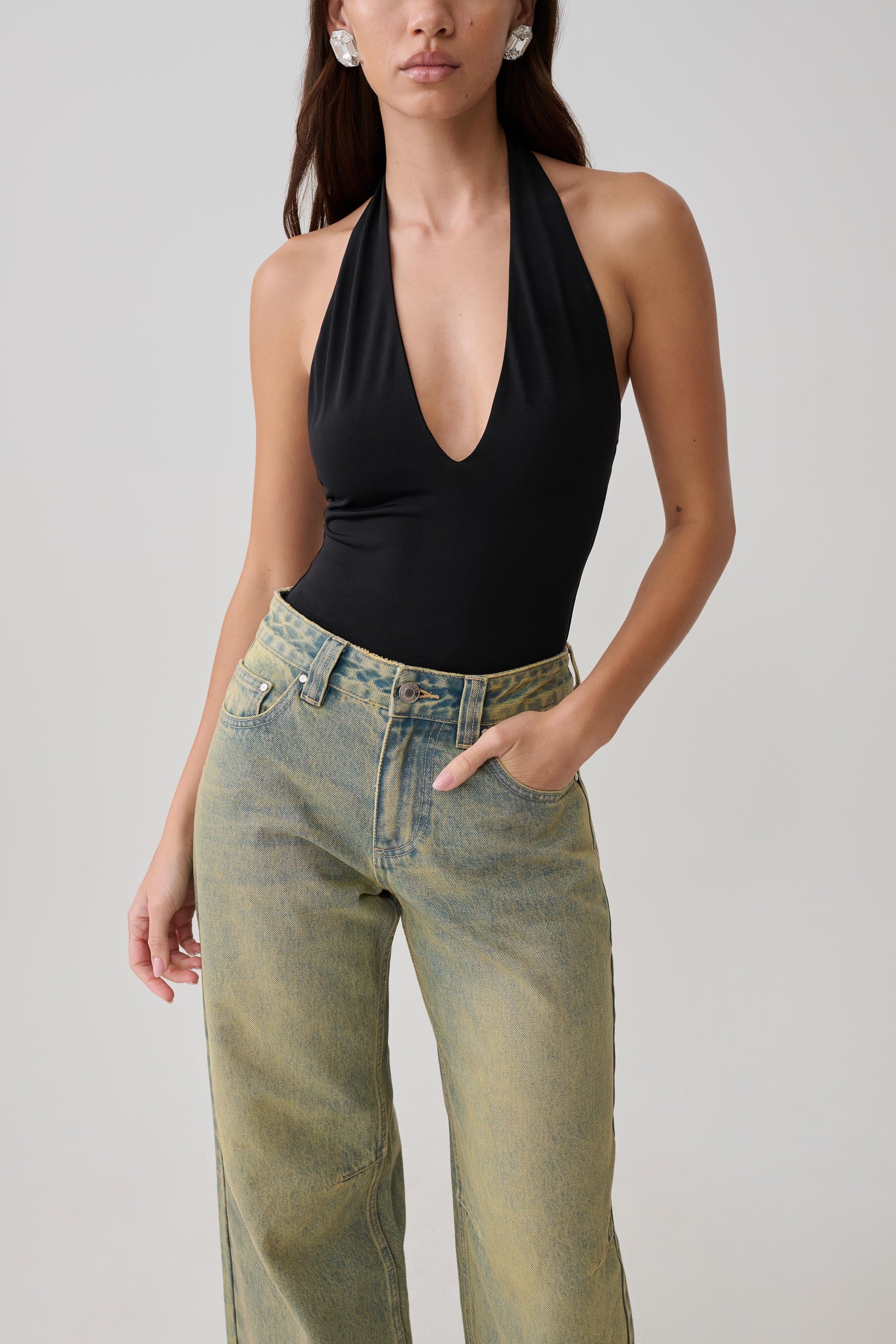 Woman wearing a black slinky halter bodysuit.