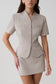 Woman wearing a grey suiting short sleeve top.