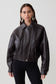 Woman wearing a brown faux leather cropped jacket.