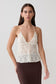 Woman wearing a white lace cami halter top.