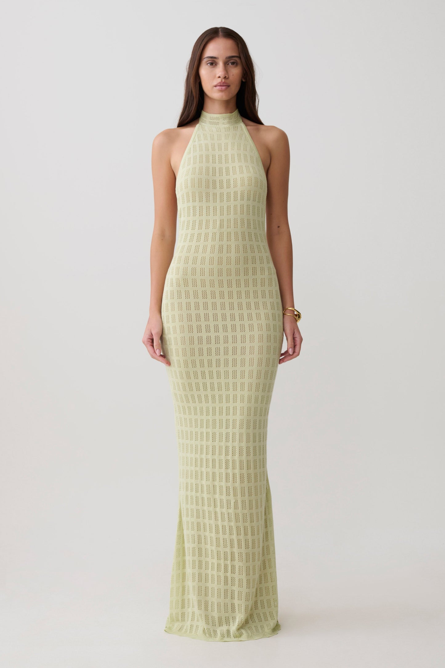 Woman wearing a light green knit halter neck dress.