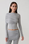 Woman wearing a grey long-sleeve overlay top.