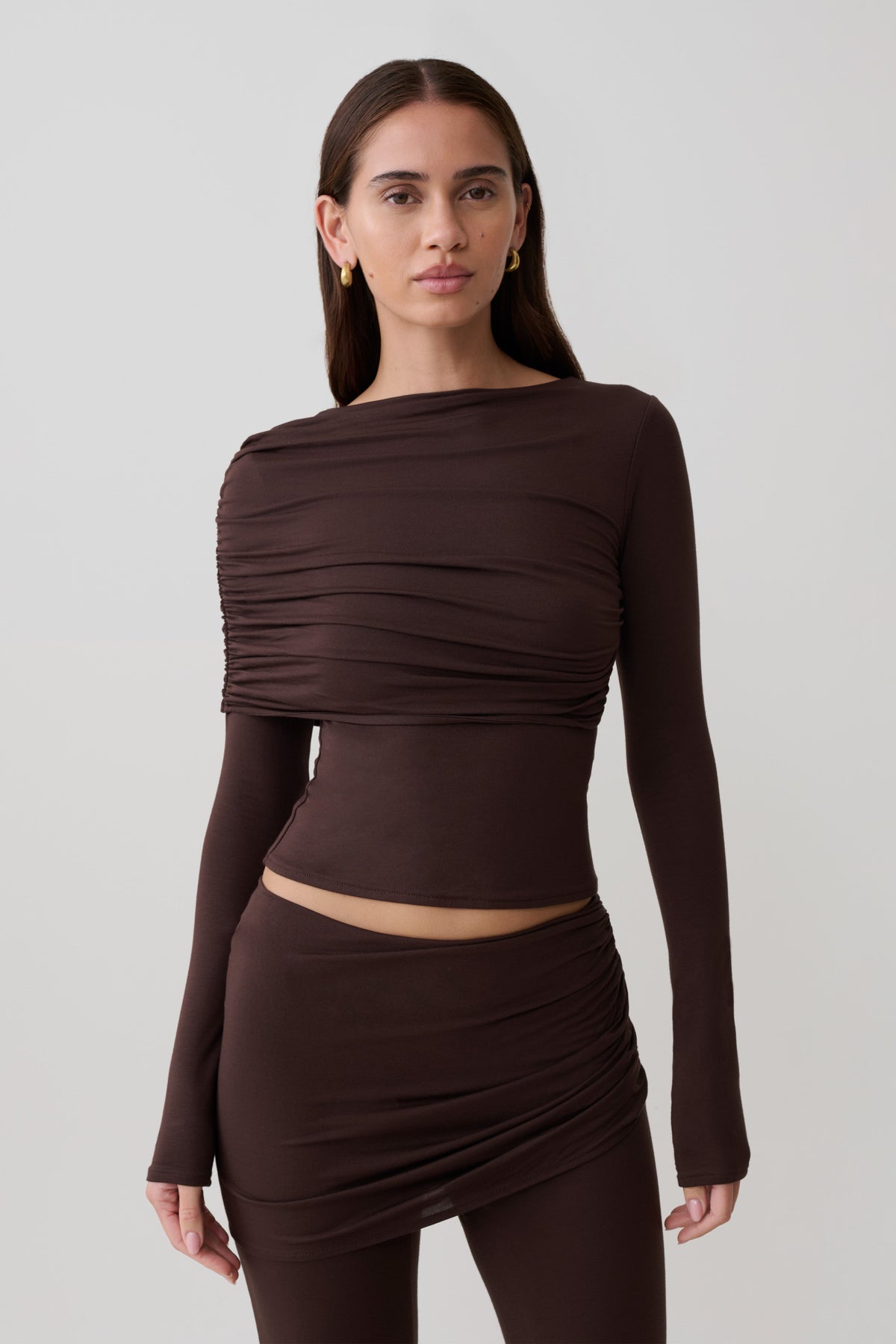 Woman wearing a brown long-sleeve overlay top.