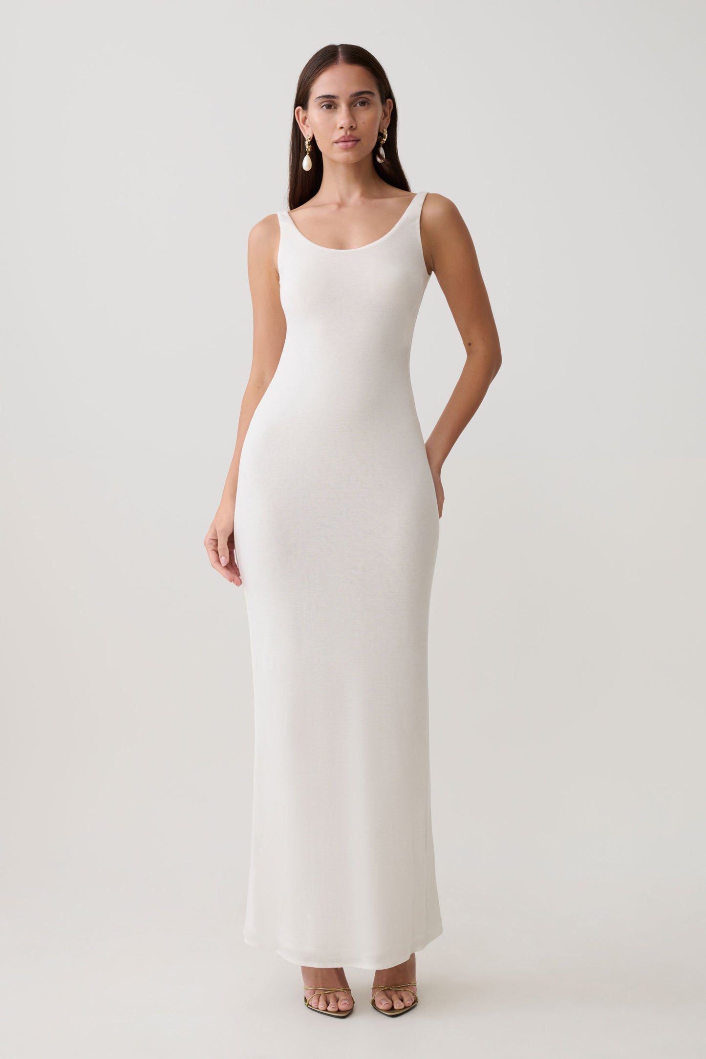 Woman wearing a white scoop neck jersey maxi dress.