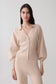 Woman wearing a beige knit blouson sleeve cardigan.