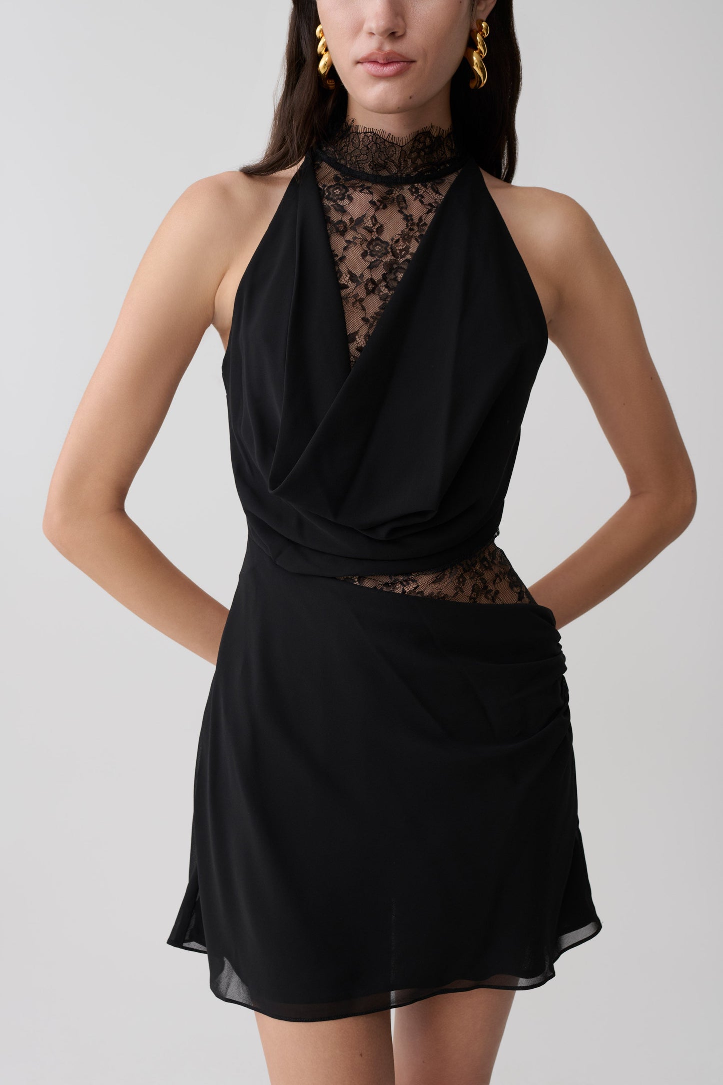 Woman wearing a black chiffon And lace halter mini dress.
