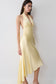 Woman wearing a yellow halter midi dress with an asymmetric hem.