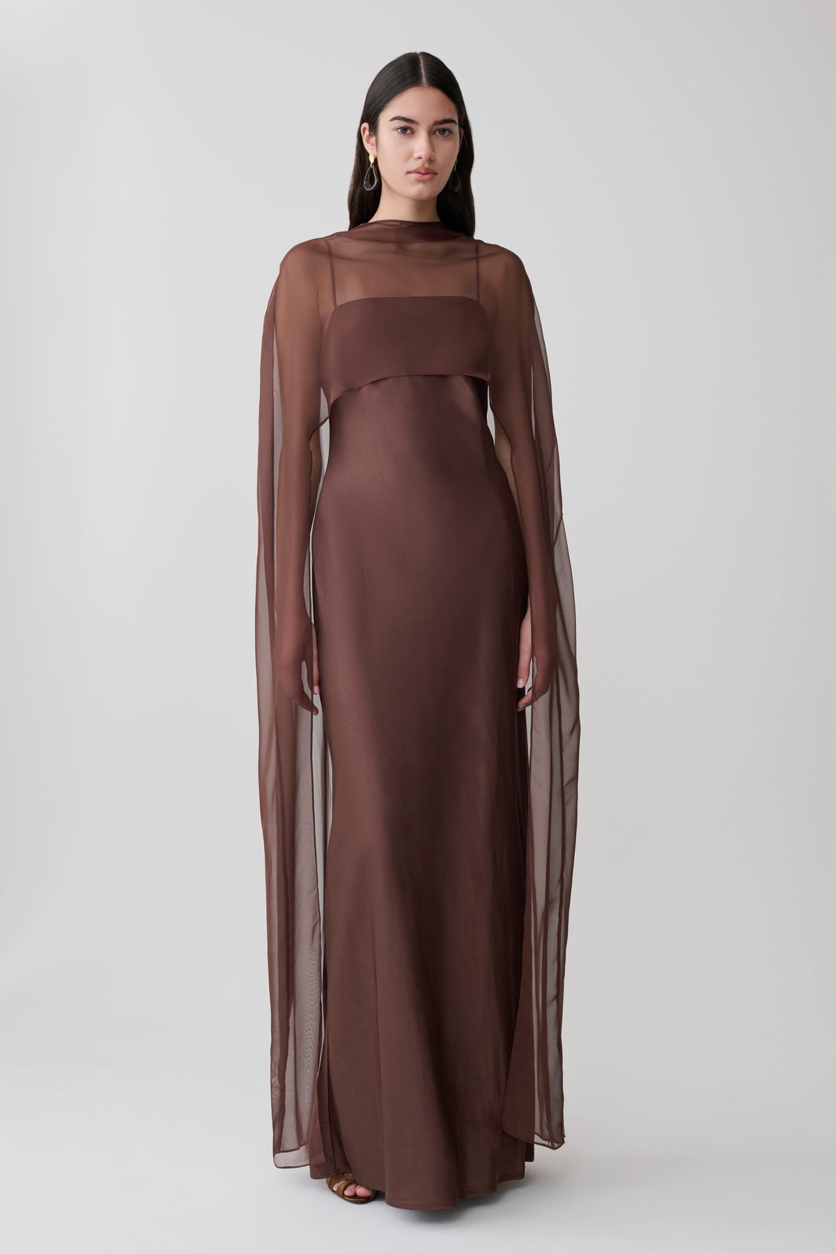 Woman wearing a brown chiffon overlay maxi dress.