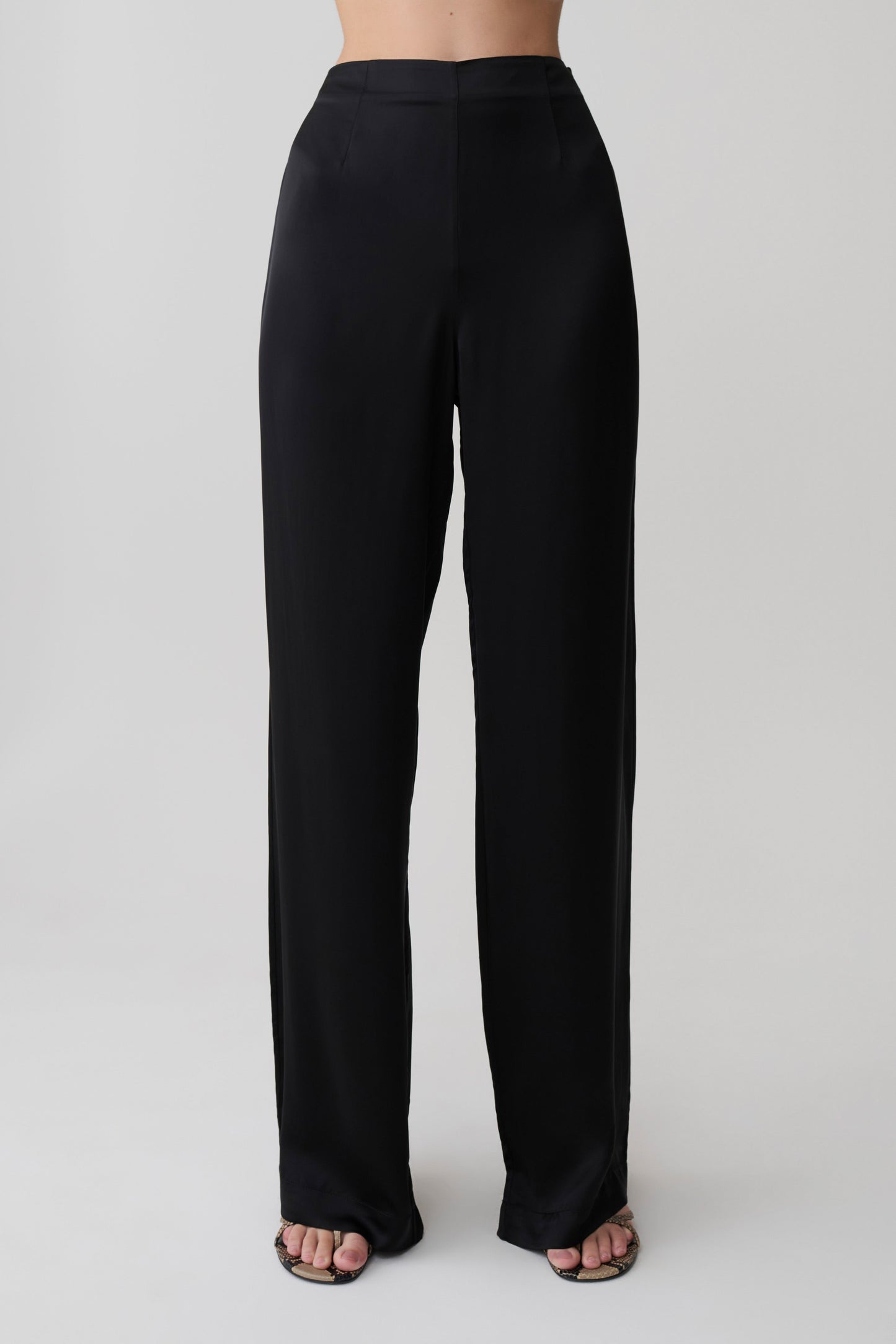 Woman wearing black straight leg satin pants.