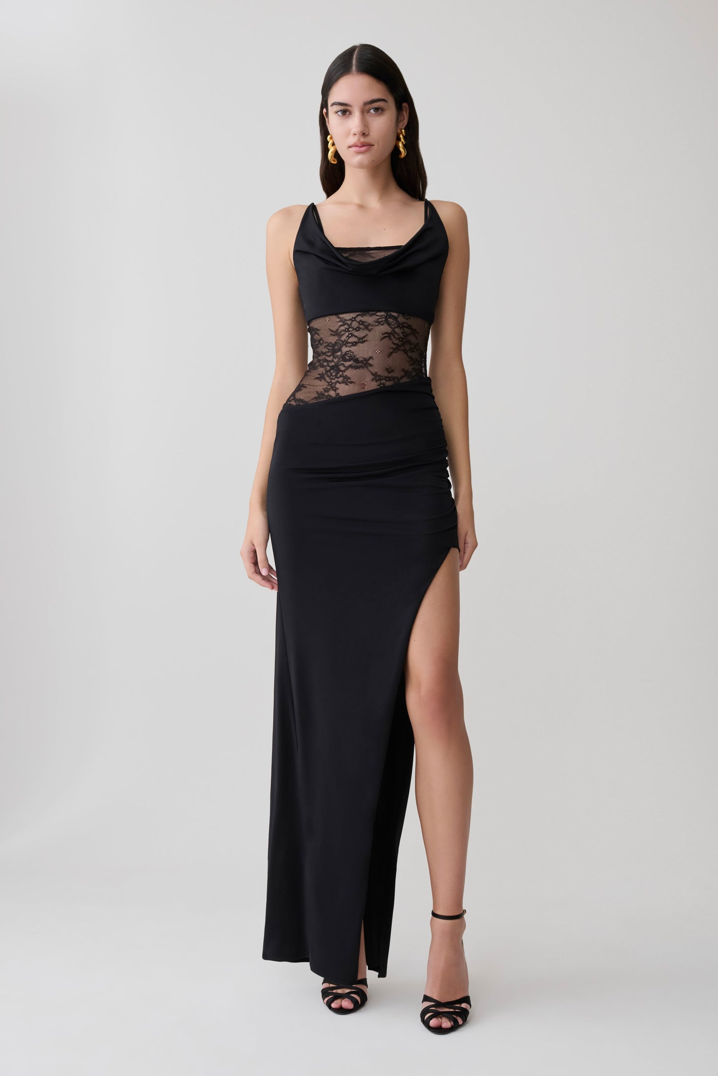 Woman wearing a black draped slinky and lace maxi dress.