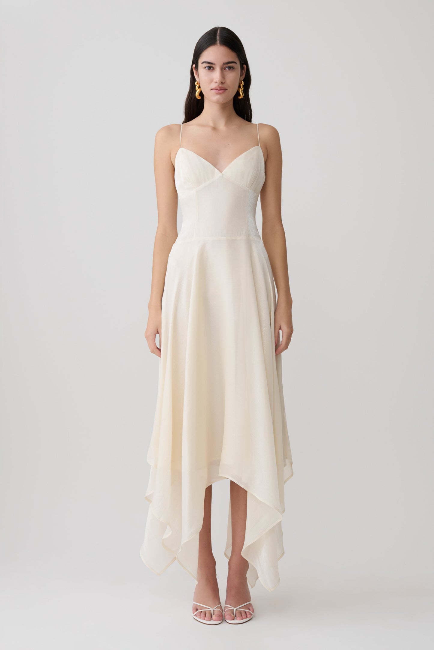 Woman wearing a white satin asymmetric hem maxi dress.
