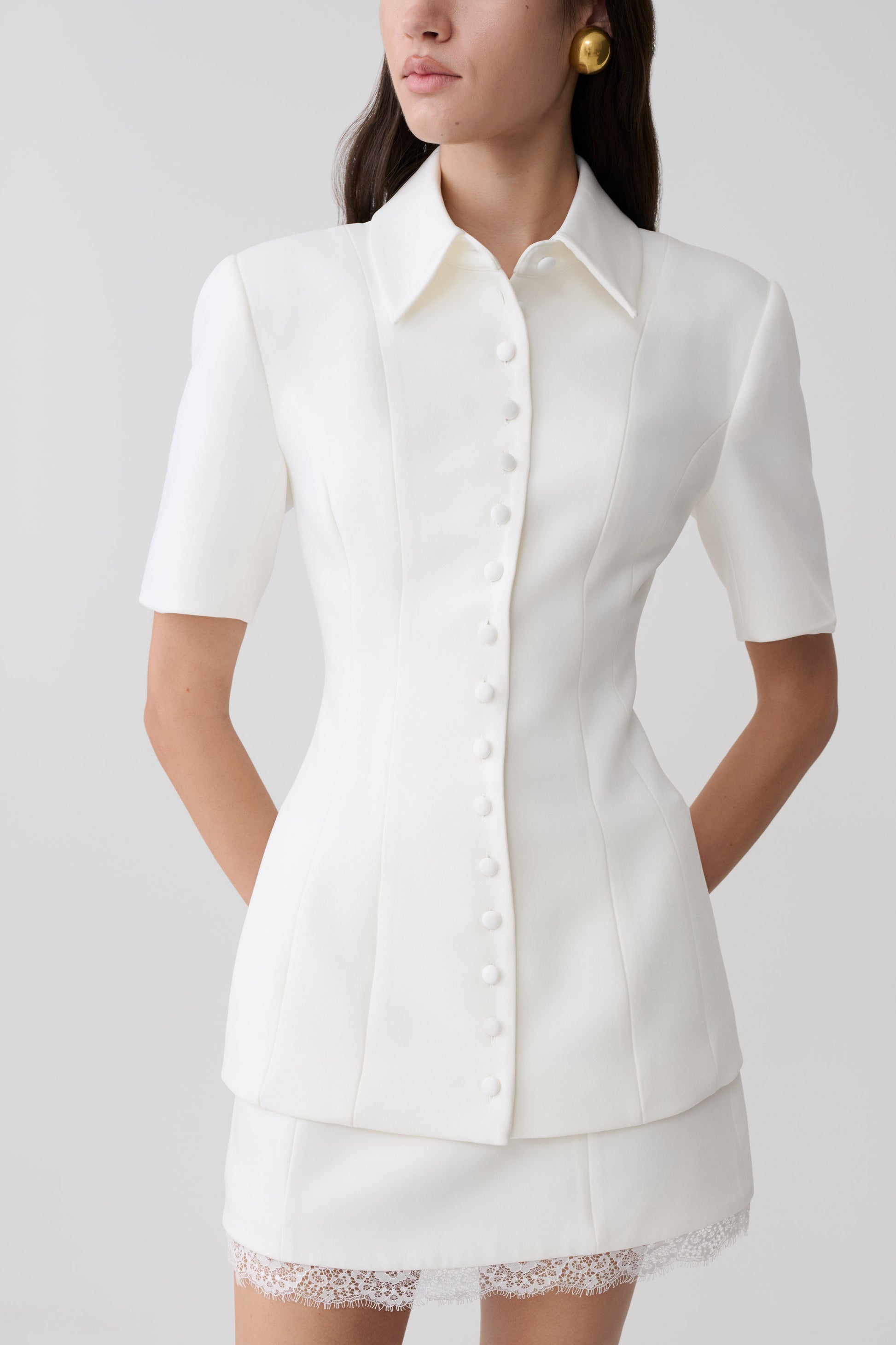 Woman wearing white button up short sleeved top.