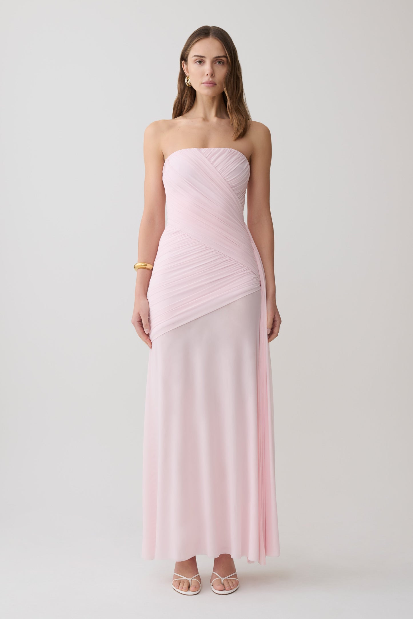 Woman wearing a pink strapless ruched mesh maxi dress.