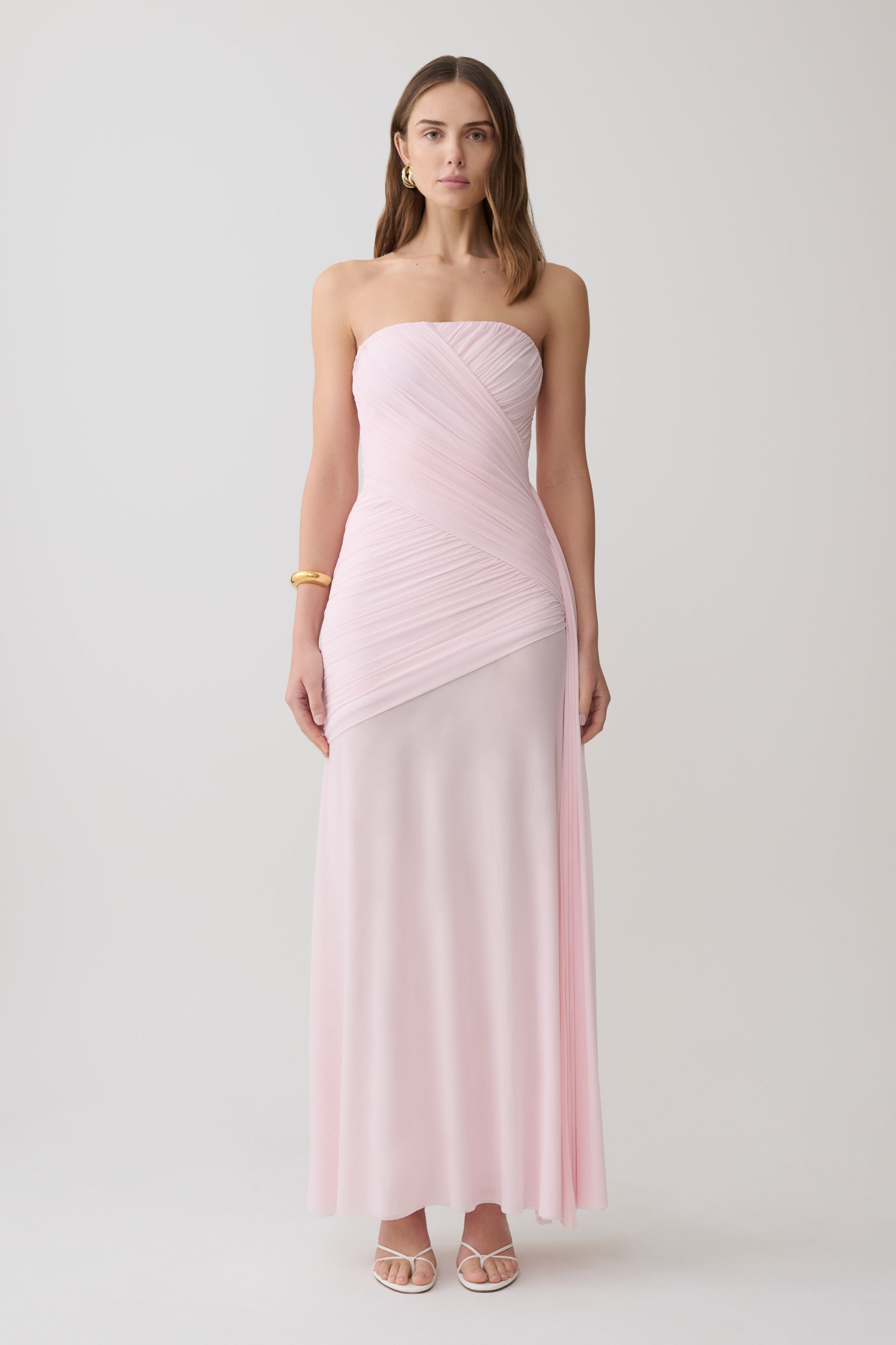 Woman wearing a pink strapless ruched mesh maxi dress.