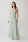 Woman wearing a light green strapless ruched mesh maxi dress.