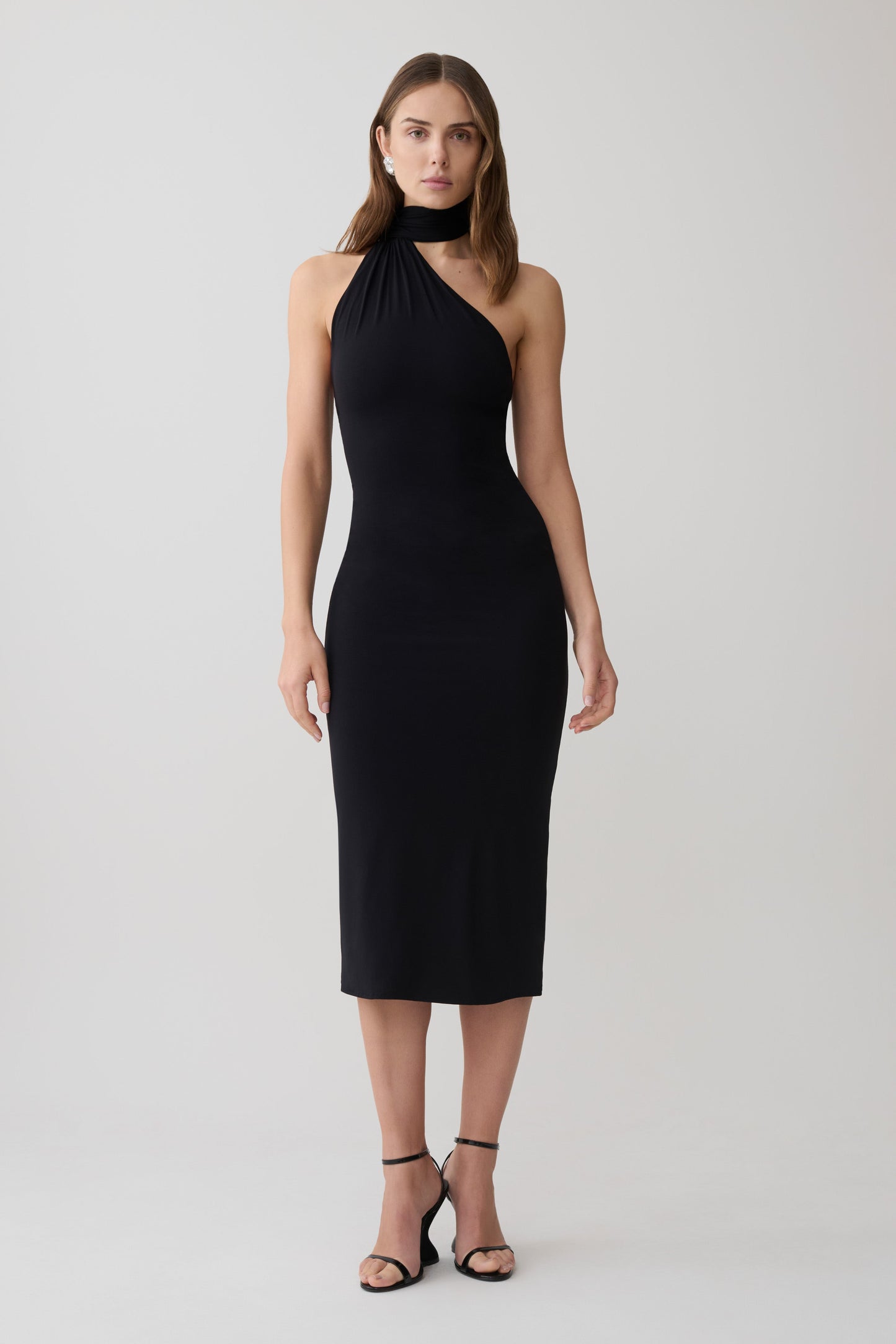 Woman wearing a black one shoulder tie midi dress.