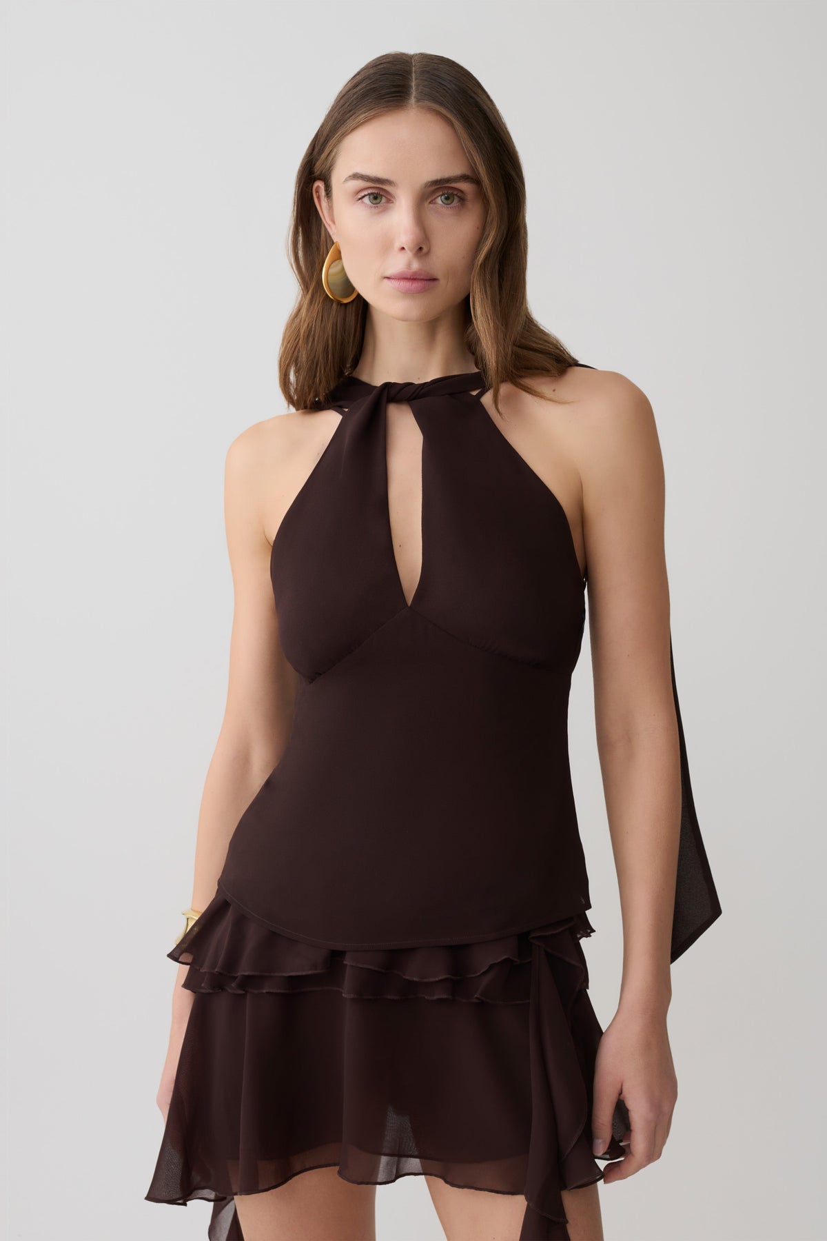Woman wearing a brown chiffon halter sleeveless top with matching mini skirt.
