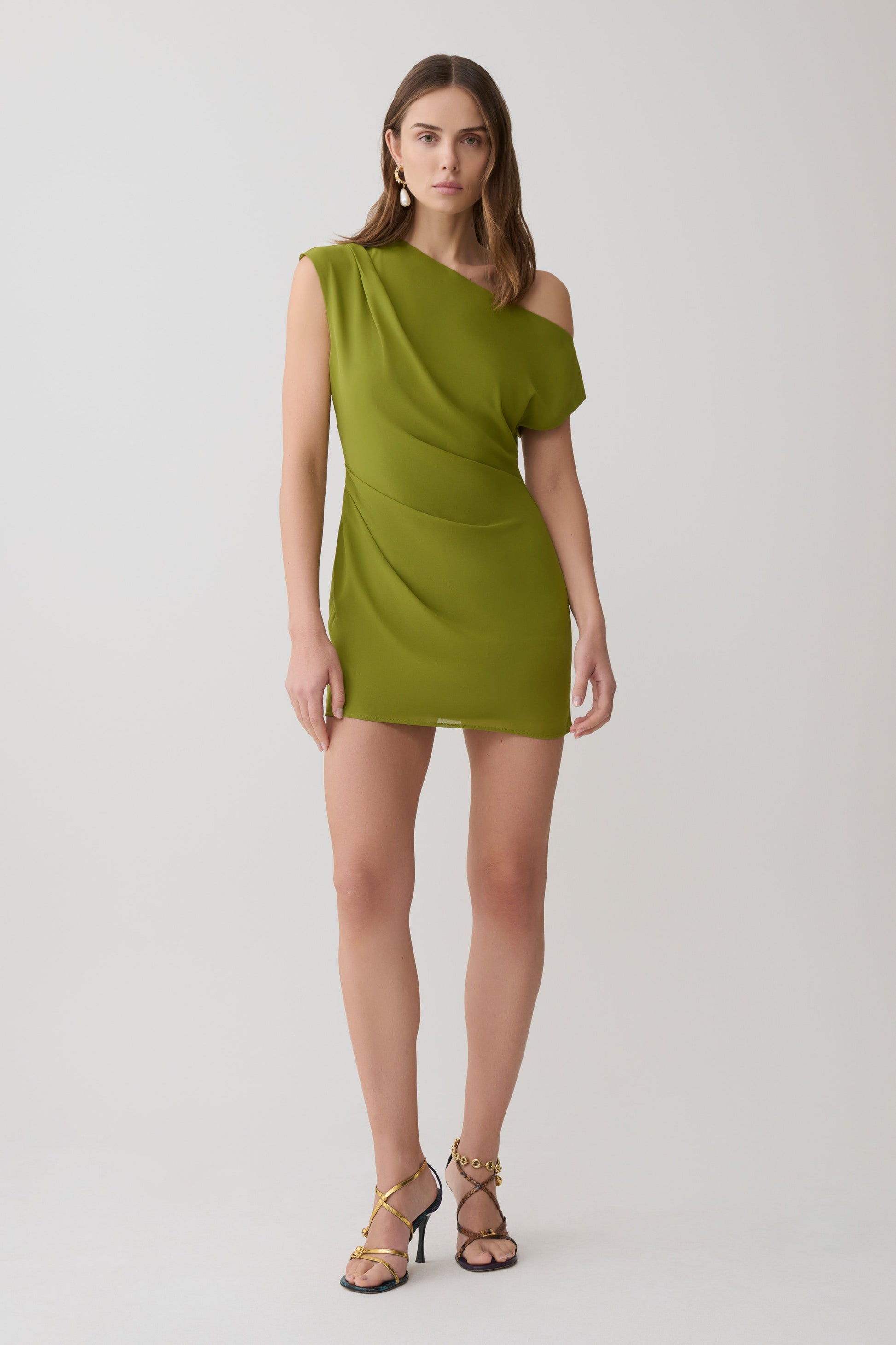 Woman wearing a green asymmetric neckline mini dress.