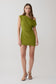 Woman wearing a green asymmetric neckline mini dress.