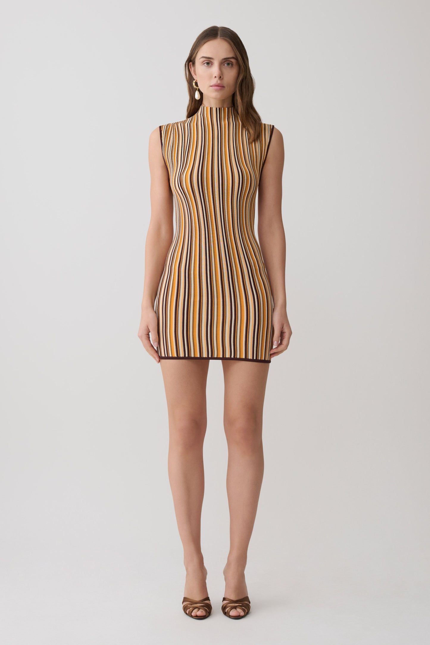 Woman wearing a brown and orange striped sleeveless mini dress.