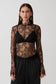 Woman wearing a black high neck long sleeve lace top.