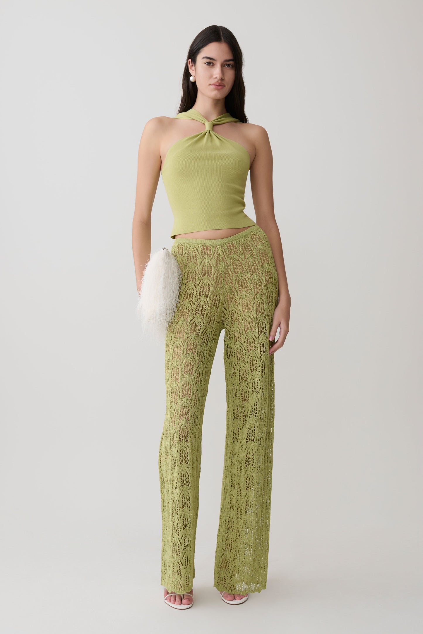 Woman wearing a green twist front knit top with matching crochet pants.