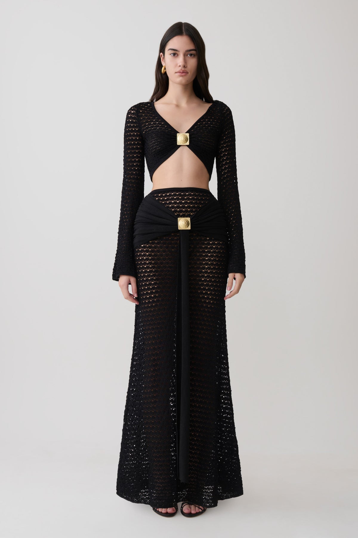 Woman wearing crochet long sleeve cropped top with matching maxi skirt.