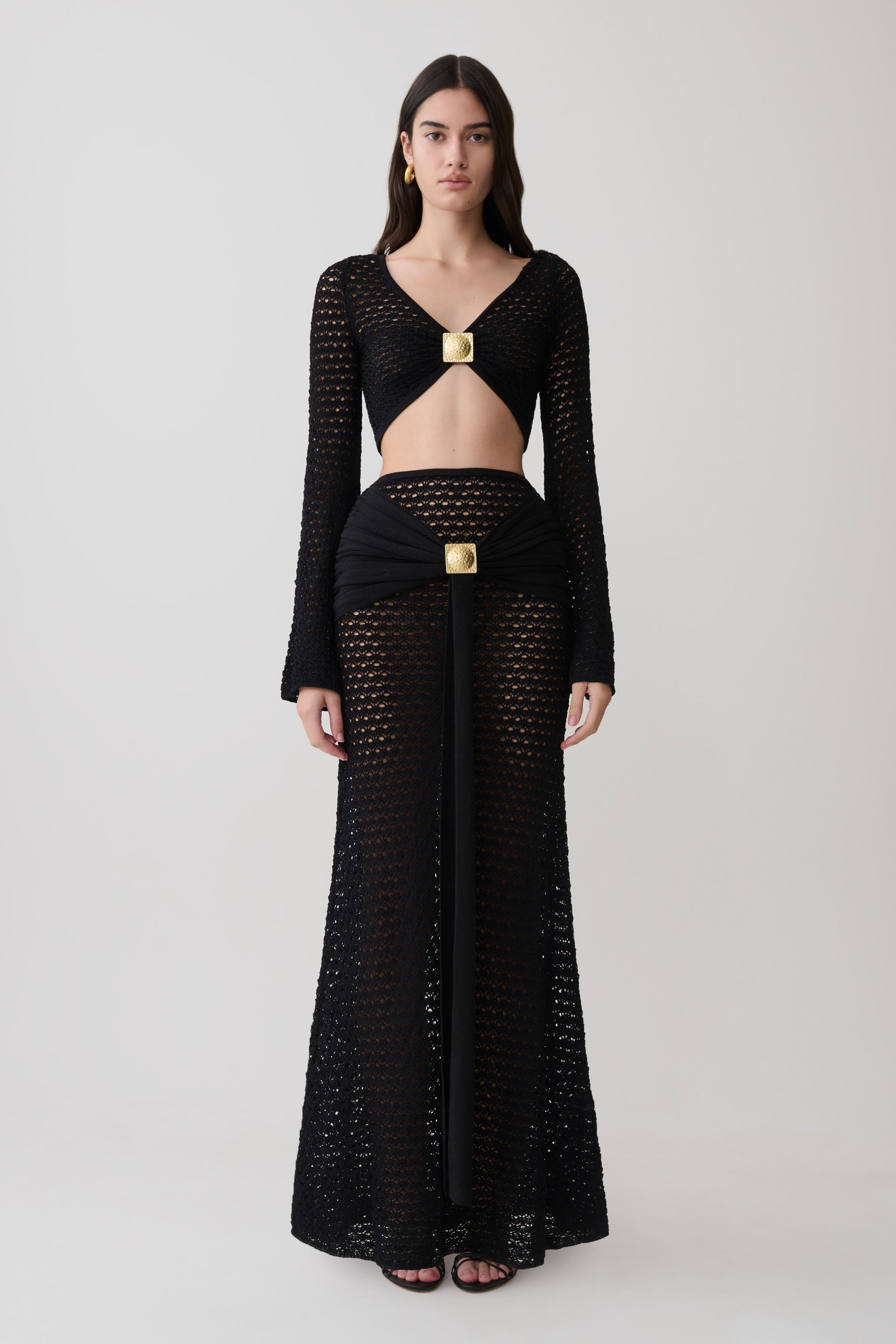 Woman wearing crochet long sleeve cropped top with matching maxi skirt.