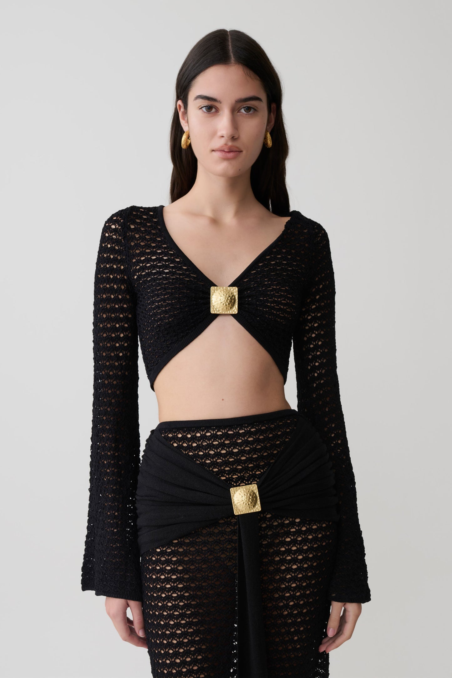 Woman wearing a black crochet long sleeve cropped top.