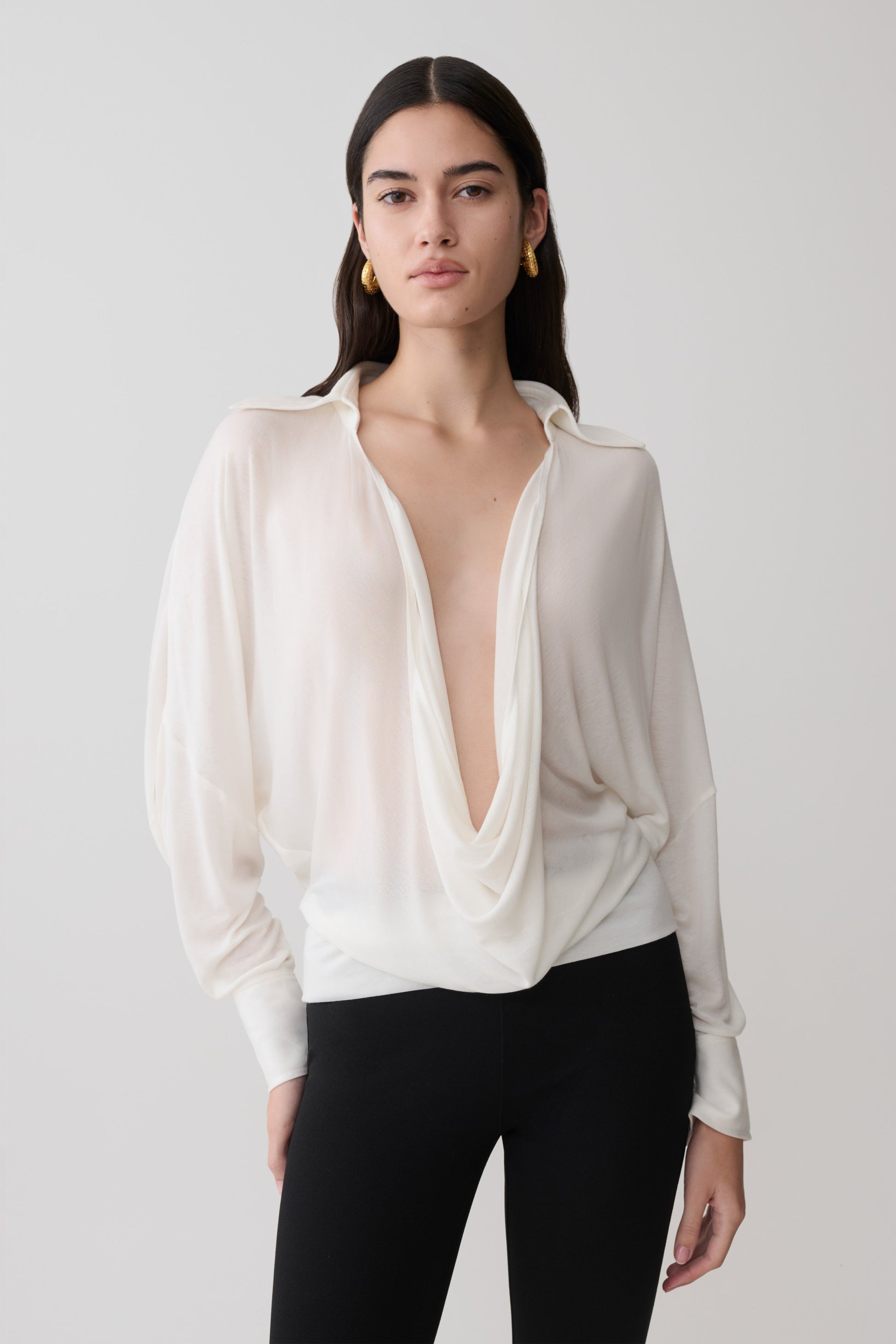 Woman wearing a white blouse with a plunging neckline.