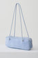 A light blue suede shoulder bag with a long, slender cylindrical body and matching shoulder straps, shown on a clean white studio background.