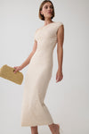 A woman models a one-shoulder, ruched midi dress in cream, holding a woven straw clutch against a plain light gray studio background.