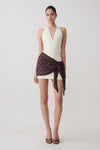 Woman wearing a mini dress with brown crochet overlay.