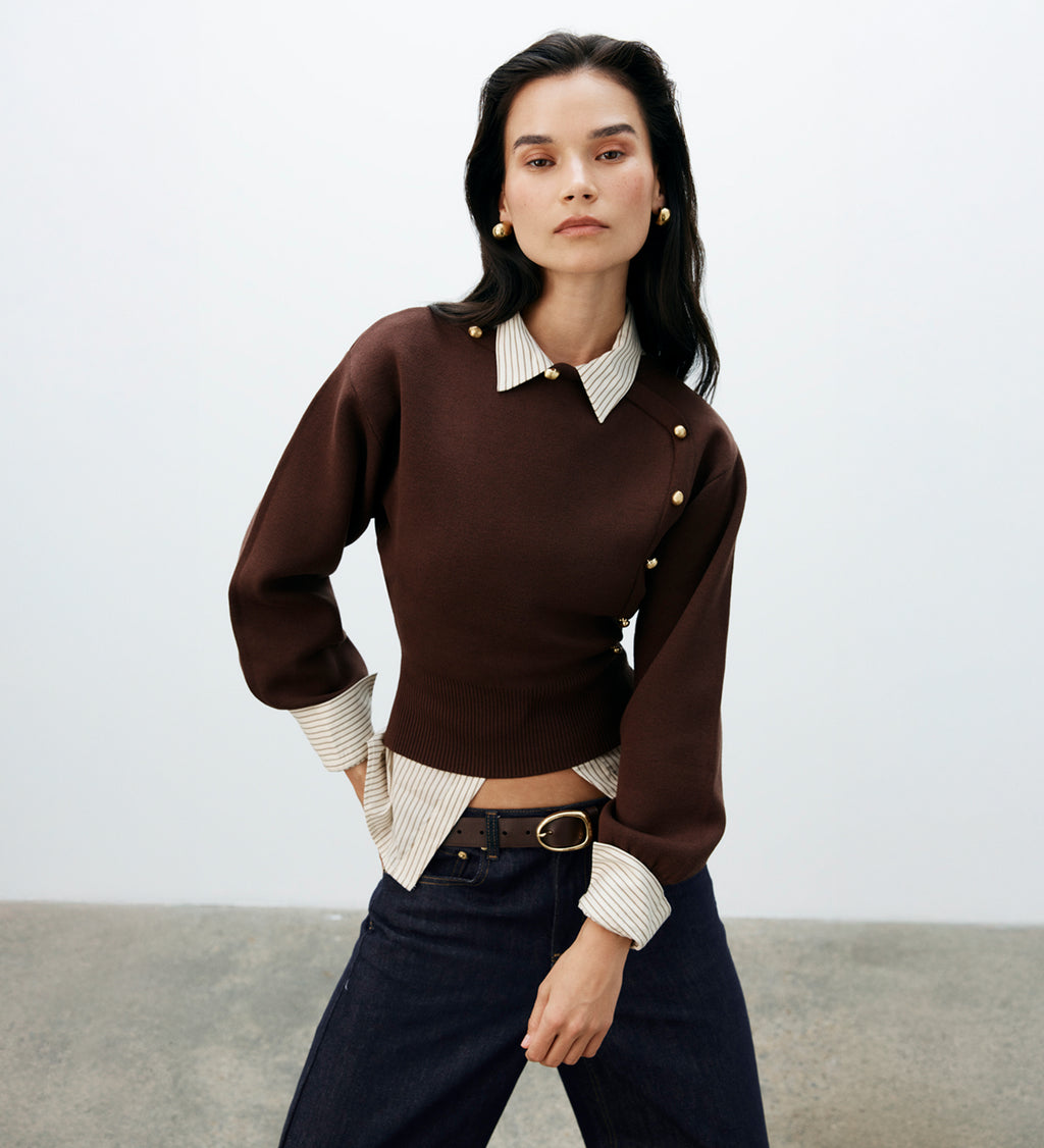 Woman wearing a brown sweater over a collared shirt.