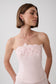A woman wearing a pale pink strapless corset-style top with floral applique across the bust, photographed against a light gray studio background.
