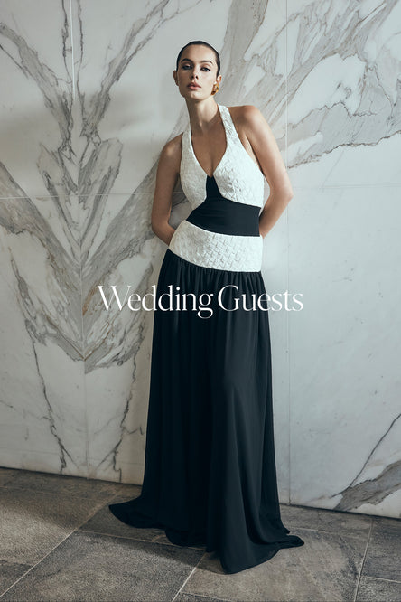 Woman in a black and white evening gown against a marble wall.