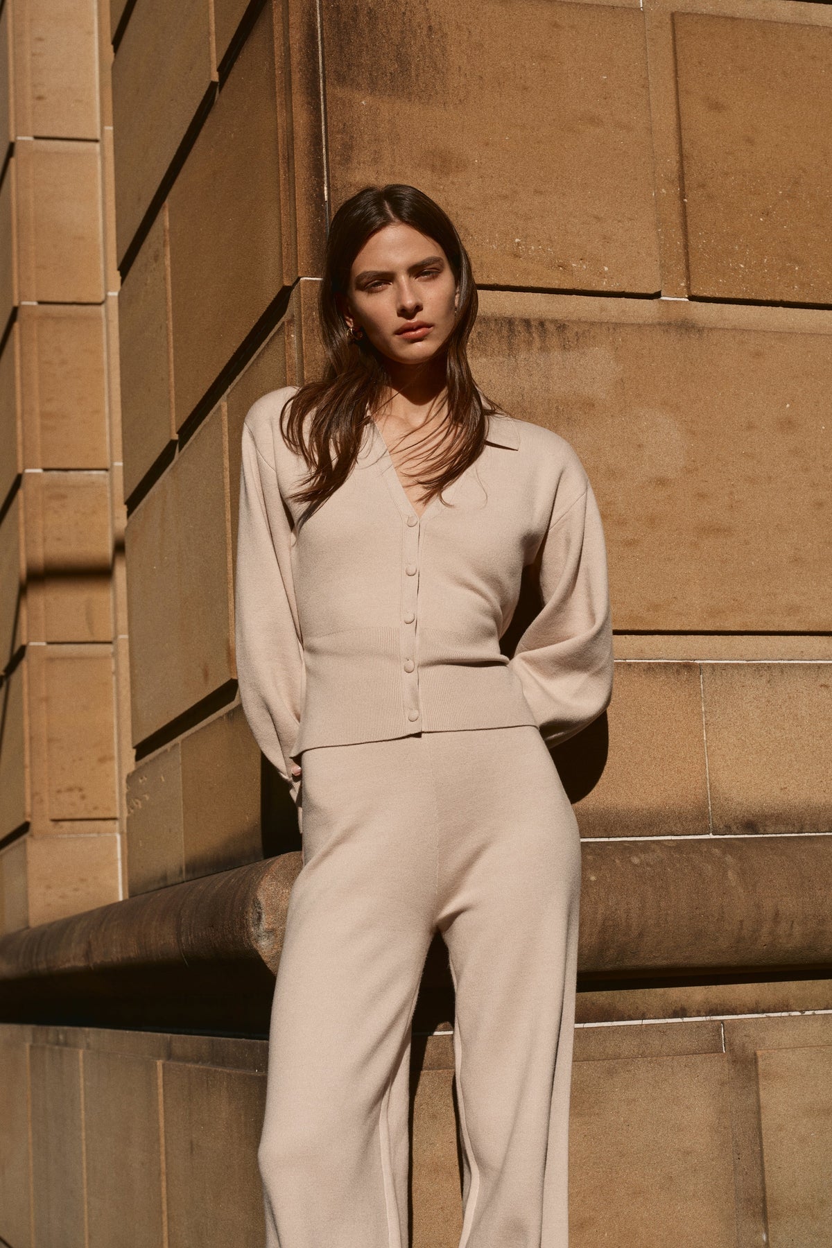 Woman wearing a beige knit blouson sleeve cardigan.